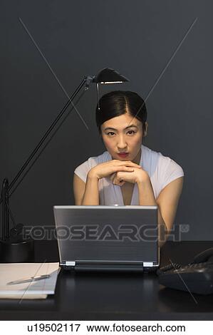 Stock Photo - Businesswoman working on laptop at night. Fotosearch