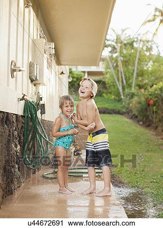 Stock Image - Children (2-3, 6-7) refreshing at outdoor shower. Fotosearch