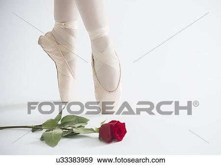 Stock Photo - Close up of girls (16-17) ballet shoes with red rose . Fotosearch