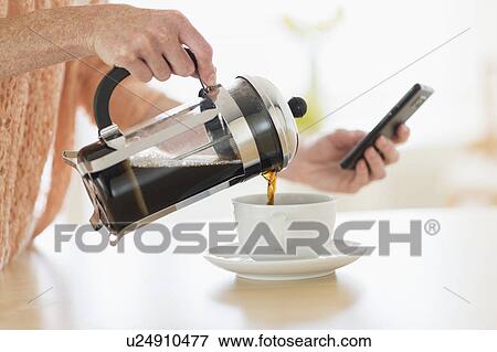 Close-up of woman pouring coffee and looking at phone View Large Photo Image Stock Photo - Close-up of woman pouring coffee and looking at phone. Fotosearch