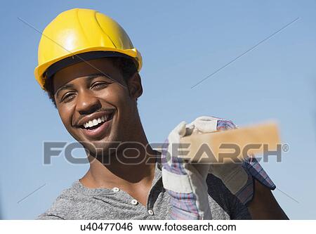 Stock Photograph - Construction worker carrying plank. Fotosearch