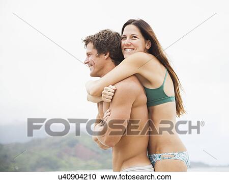 Stock Image - Couple embracing on beach. Fotosearch