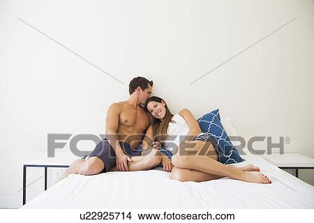 Picture - Couple lying on bed. Fotosearch
