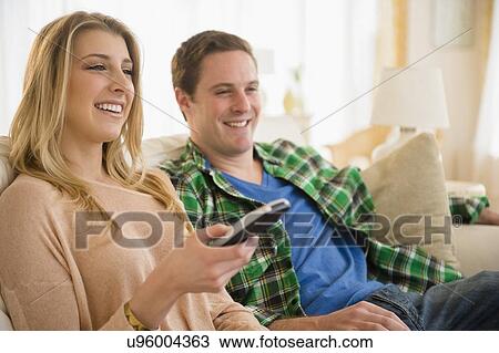 Couple on sofa watching TV View Large Photo Image Stock Image - Couple on sofa watching TV. Fotosearch