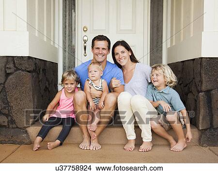 Family with three kids (6-7, 2-3, 6-11 months) sitting in front of house View Large Photo Image Picture - Family with three kids (6-7, 2-3, 6-11 months) sitting in front of house. Fotosearch