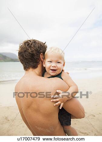 Stock Photo - Father with son (6-11 months) on beach. Fotosearch
