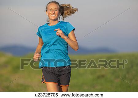 Stock Photography - Front view of young woman jogging. Fotosearch