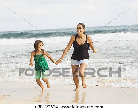 Picture - Girl (6-7) running on beach with mother. Fotosearch