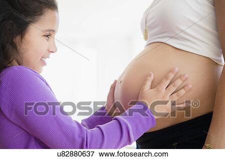 Girl (8-9) touching pregnant mother's belly View Large Photo Image Stock Photo - Girl (8-9) touching pregnant mother's belly. Fotosearch