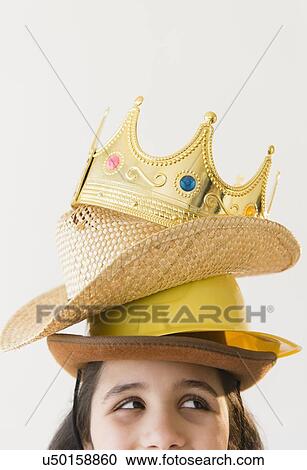 Stock Image - Girl (8-9) wearing stack of hats and crow on head. Fotosearch