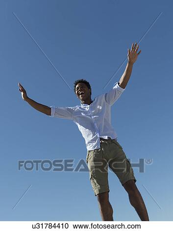 Stock Image - Happy man against clear sky. Fotosearch