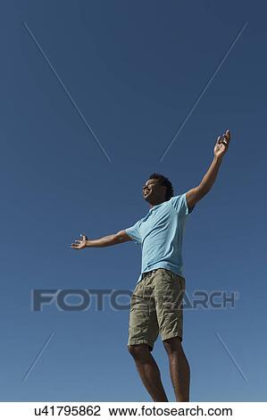 Stock Image - Happy man against clear sky. Fotosearch