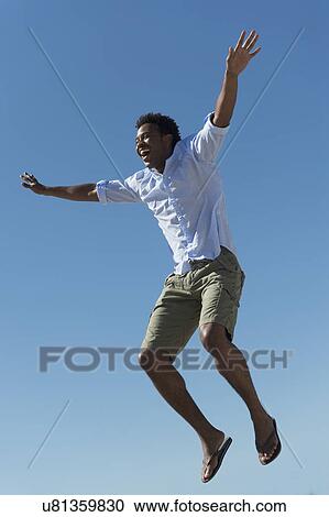 Stock Image - Happy man against clear sky. Fotosearch