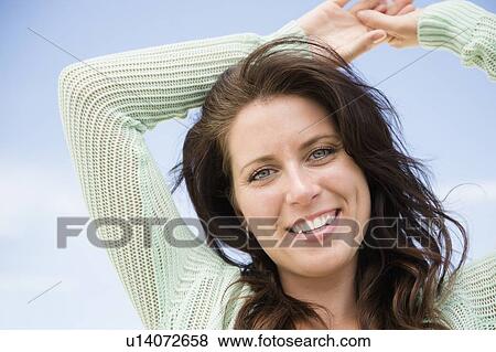 Stock Photo - Happy woman against blue sky. Fotosearch