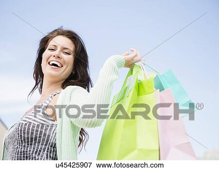 Stock Photo - Happy woman holding shopping bags. Fotosearch