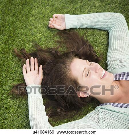 Happy woman lying on grass View Large Photo Image Stock Photo - Happy woman lying on grass. Fotosearch