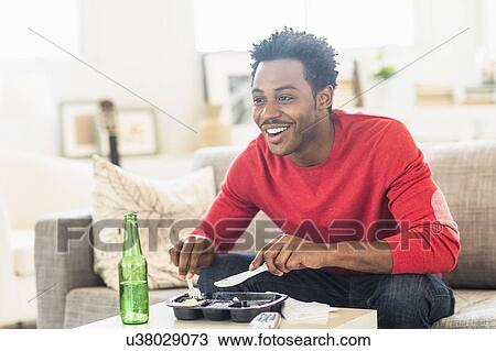 Stock Image - Man eating dinner and watching television. Fotosearch