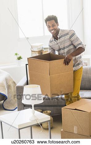 Man holding cardboard box in living room View Large Photo Image Stock Image - Man holding cardboard box in living room. Fotosearch