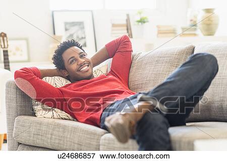 Man lying on sofa and smiling View Large Photo Image Stock Photo - Man lying on sofa and smiling. Fotosearch