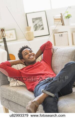 Man lying on sofa and smiling View Large Photo Image Stock Photo - Man lying on sofa and smiling. Fotosearch