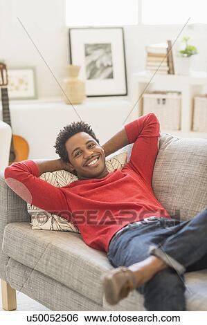 Man lying on sofa and smiling View Large Photo Image Stock Photograph - Man lying on sofa and smiling. Fotosearch