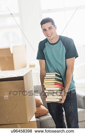 Stock Photo - Man packing books into cardboard box at home. Fotosearch