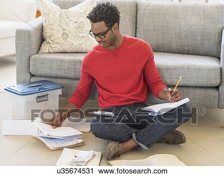 Man sitting on floor in living room and calculating bills View Large Photo Image Stock Image - Man sitting on floor in living room and calculating bills. Fotosearch