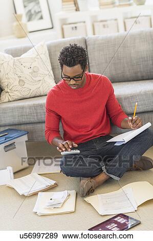 Man sitting on floor in living room and calculating bills View Large Photo Image Stock Photo - Man sitting on floor in living room and calculating bills. Fotosearch