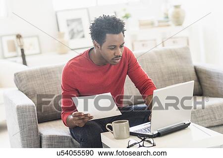 Man sitting on sofa and using laptop View Large Photo Image Stock Image - Man sitting on sofa and using laptop. Fotosearch