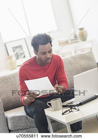 Man sitting on sofa and using laptop View Large Photo Image Stock Image - Man sitting on sofa and using laptop. Fotosearch