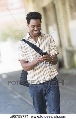 Man walking on street and text messaging View Large Photo Image Stock Image - Man walking on street and text messaging. Fotosearch