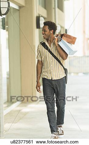 Man walking on street with shopping bags View Large Photo Image Stock Image - Man walking on street with shopping bags. Fotosearch