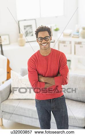 Stock Photo - Man wearing spectacles standing in living room. Fotosearch