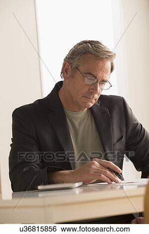 Stock Photograph - Mature business man concentrating on work. Fotosearch