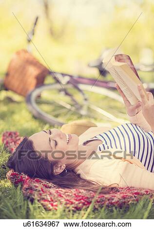 Stock Photo - Mid adult woman reading book. Fotosearch