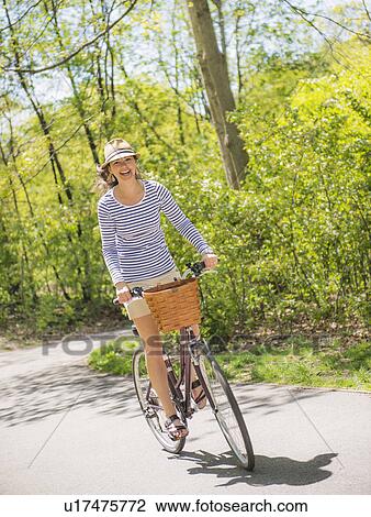 Stock Image - Mid adult woman riding bicycle. Fotosearch