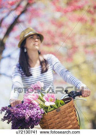Stock Image - Mid adult woman riding bicycle. Fotosearch