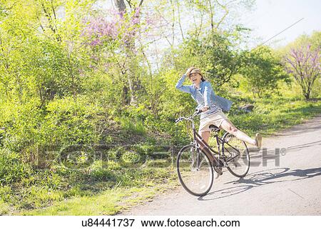 Stock Photo - Mid adult woman riding bicycle. Fotosearch