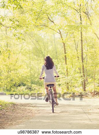 Stock Photo - Mid adult woman riding bicycle. Fotosearch