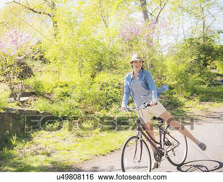 Mid adult woman riding bicycle View Large Photo Image Stock Photograph - Mid adult woman riding bicycle. Fotosearch