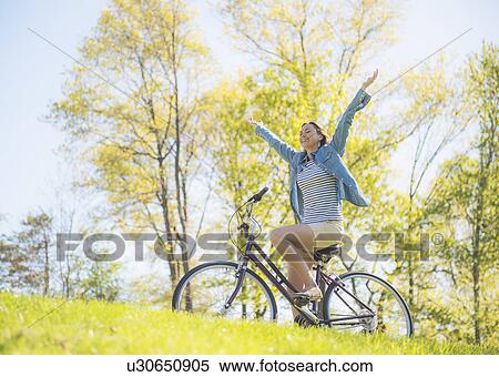 Mid adult woman riding bicycle View Large Photo Image Stock Photography - Mid adult woman riding bicycle. Fotosearch