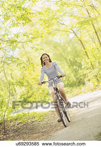 Mid adult woman riding bicycle View Large Photo Image Stock Photography - Mid adult woman riding bicycle. Fotosearch