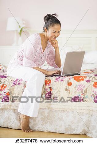 Stock Photo - Mid adult woman using laptop. Fotosearch