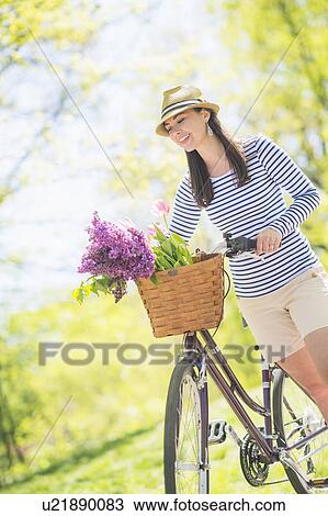 Stock Image - Mid adult woman with bicycle. Fotosearch
