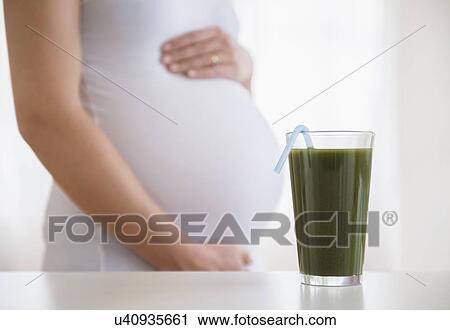 Mid section of pregnant woman, green smoothie in front View Large Photo Image Stock Image - Mid section of pregnant woman, green smoothie in front. Fotosearch