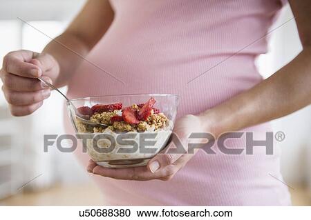 Mid section of pregnant woman holding bowl with granola View Large Photo Image Stock Image - Mid section of pregnant woman holding bowl with granola. Fotosearch