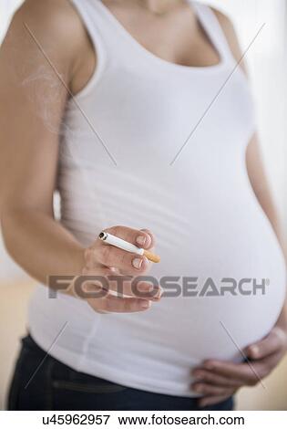 Stock Photo - Mid section of pregnant woman holding cigarrete. Fotosearch