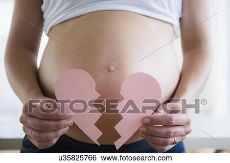Mid section of pregnant woman holding broken paper heart View Large Photo Image Stock Photograph - Mid section of pregnant woman holding broken paper heart. Fotosearch