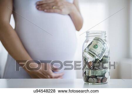 Mid section of pregnant woman, jar with money in front View Large Photo Image Stock Photo - Mid section of pregnant woman, jar with money in front. Fotosearch