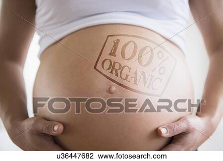 Stock Image - Mid section of pregnant woman with label on belly. Fotosearch